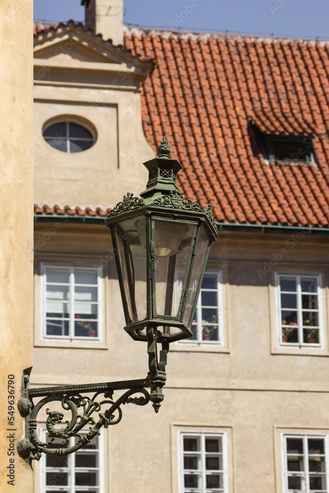 Antique street lantern on wall in the old town of Prague, Czech Republic. Old street light against windows and roof tile