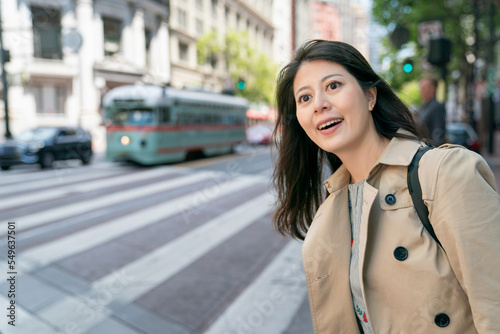 amazed asian Japanese woman tourist enjoying cityscape while waiting her bus to come at roadside near zebra crossing in san Francisco California usa © PR Image Factory