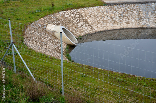 behind a wire fence is a sluice gate. the slide can be set to a certain water level. it holds back the flushes from the sewage system. reservoir as a source of water for making snow on the ski slopes  photo