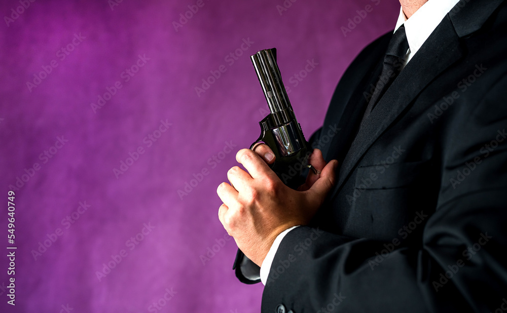 robber in tuxedo with gun at chest level isolated on plain background. robber in tuxedo with gun at chest level isolated on plain background.