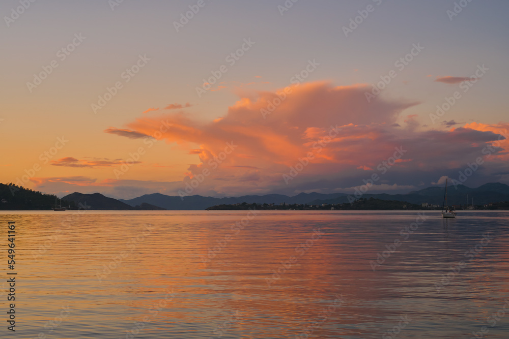 Evening warm landscape of Fethiye Bay, blurred background of a mountain range and cumulus clouds in the rays of the sun, an idea for a background
