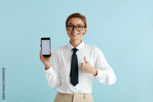 Happy Businesswoman Showing Smartphone. Caucasian Lady Smiling while Showing Cellphone, Recommended App, Enjoying Mobile Service. Empty Copy Space for Advertisement, Indoor Studio Shot 