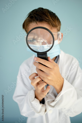 cool funny bub dressed as scientist with big magnifying glass and black glasses in front of blue background