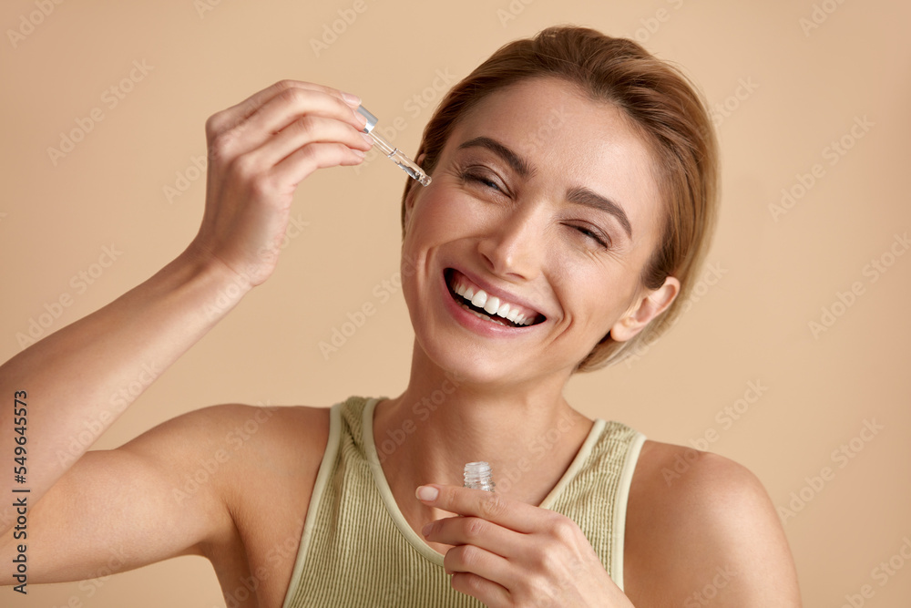 Woman Applying Serum on Face. Woman Applying Essential Oil On Facial Skin And Looking at Camera. Beautiful Model Moisturizing Derma With Natural Vitamin E, Serum Collagen And Hyaluronic Acid Woman Applying Serum on Face. Woman Applying Essential Oil On Facial Skin And Looking at Camera. Beautiful Model Moisturizing Derma With Natural Vitamin E, Serum Collagen And Hyaluronic Acid
