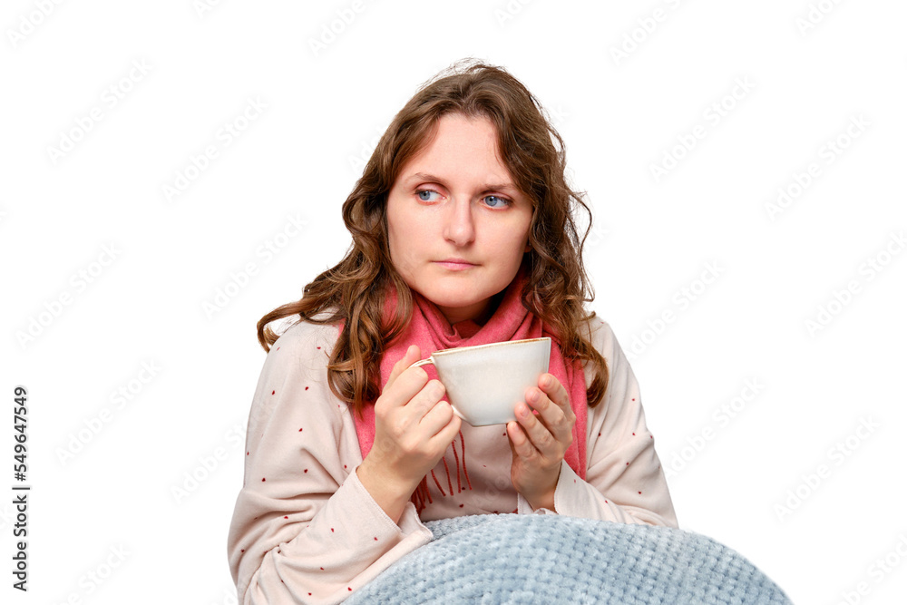A sick woman is sitting on her home bed with a cup, isolated on a white background. Adult ill woman with a red scarf sitting on a bed in a white bedroom, female aged 35 years A sick woman is sitting on her home bed with a cup, isolated on a white background. Adult ill woman with a red scarf sitting on a bed in a white bedroom, female aged 35 years