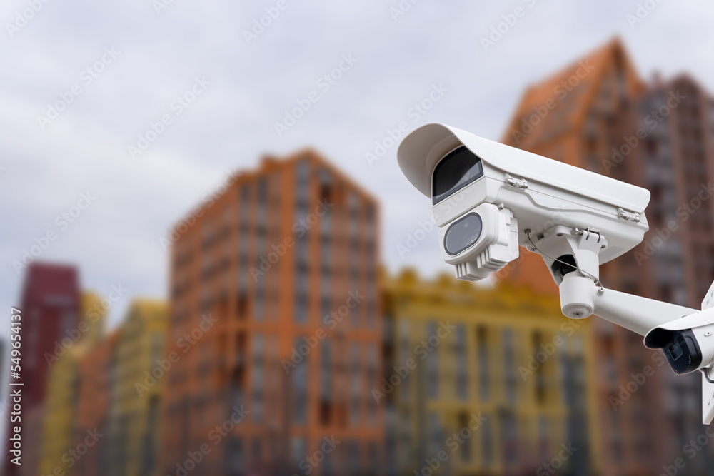 Modern public CCTV camera with blur building background. Recording cameras for monitoring all day and night. Concept of surveillance and monitoring with copy space.