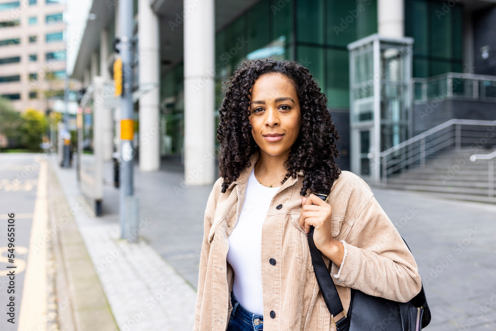 Confident woman with curly hair standing on footpath Confident woman with curly hair standing on footpath