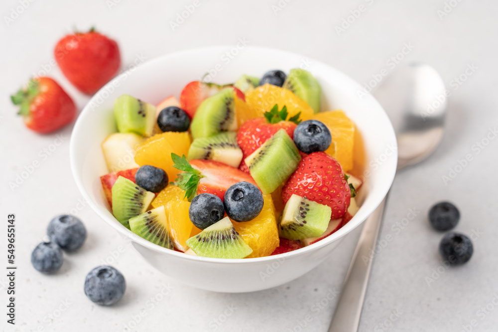 Bowl with fruit salad on light background. Strawberry, blueberry, kiwi, orange, apple slices. Healthy quick snack concept Bowl with fruit salad on light background. Strawberry, blueberry, kiwi, orange, apple slices. Healthy quick snack concept