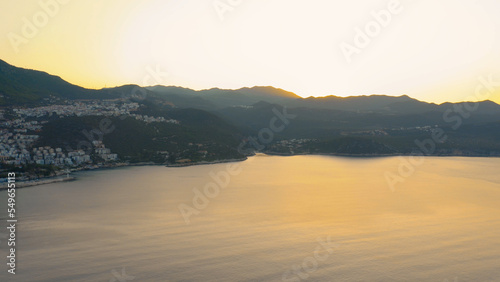 Beautiful seascape with mountains and orange sunset sky. Panorama of resort town in the evening. Picturesque nature landscape.