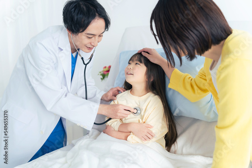 入院している女の子を診察する医師 小児科医