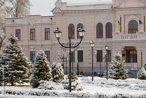 Beautiful town Izmail on south of Ukraine, winter landscape with buildings, trees, street lamps covered with snow and cloudy sky photo