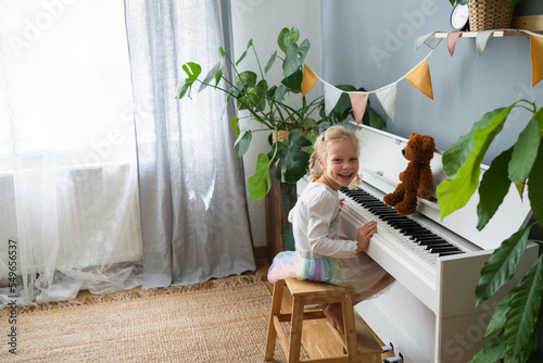 Happy girl sitting on stool by piano at home