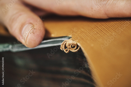 Hands of craftsperson carving guitar in workshop photo