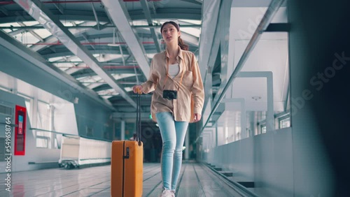 Happiness smiling asian woman passenger walking with a yellow suitcase luggage at airport terminal, Woman on way to flight boarding gate, Tourist journey trip concept