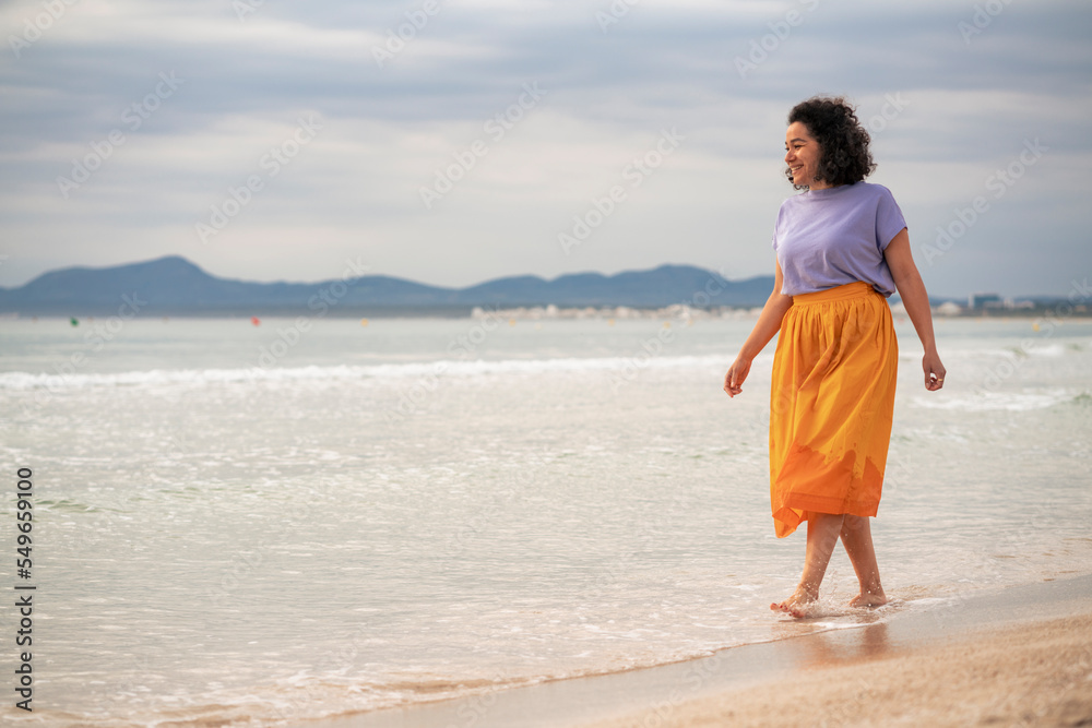 Smiling woman walking on beach at sunset