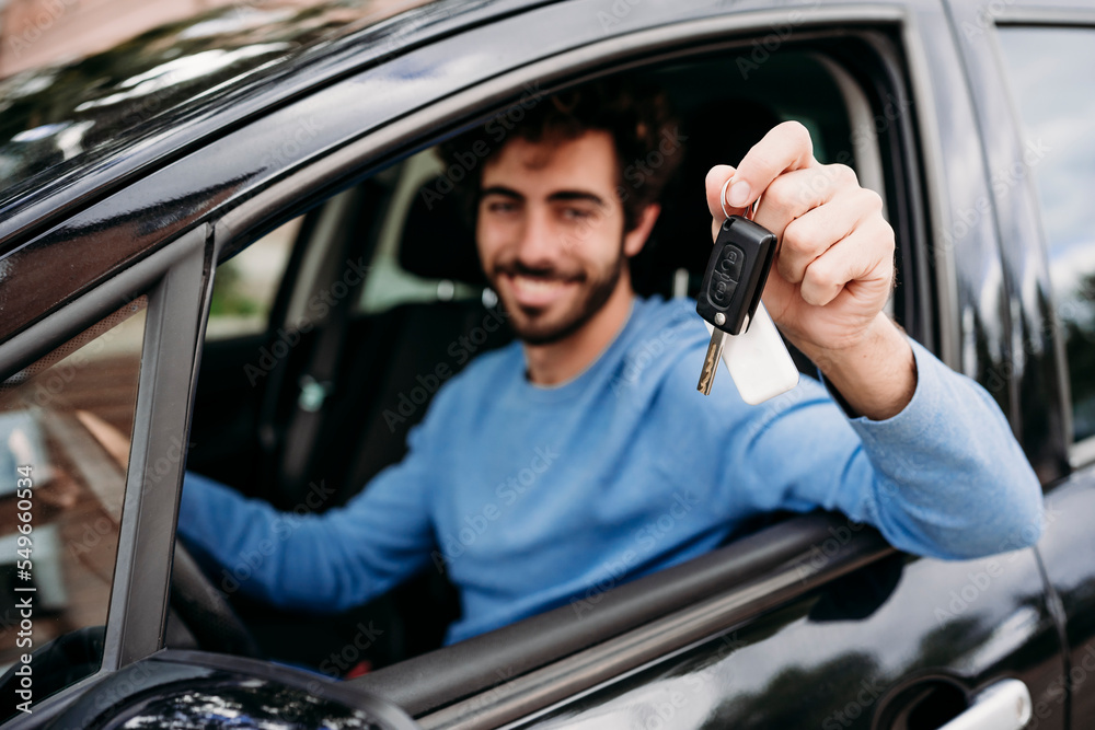 Young man showing key sitting in car Young man showing key sitting in car