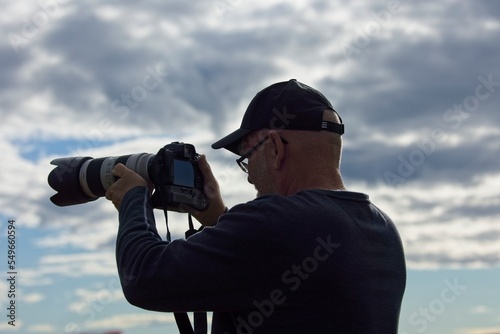 Bald male middle-aged photographer in profile with a cap on his head