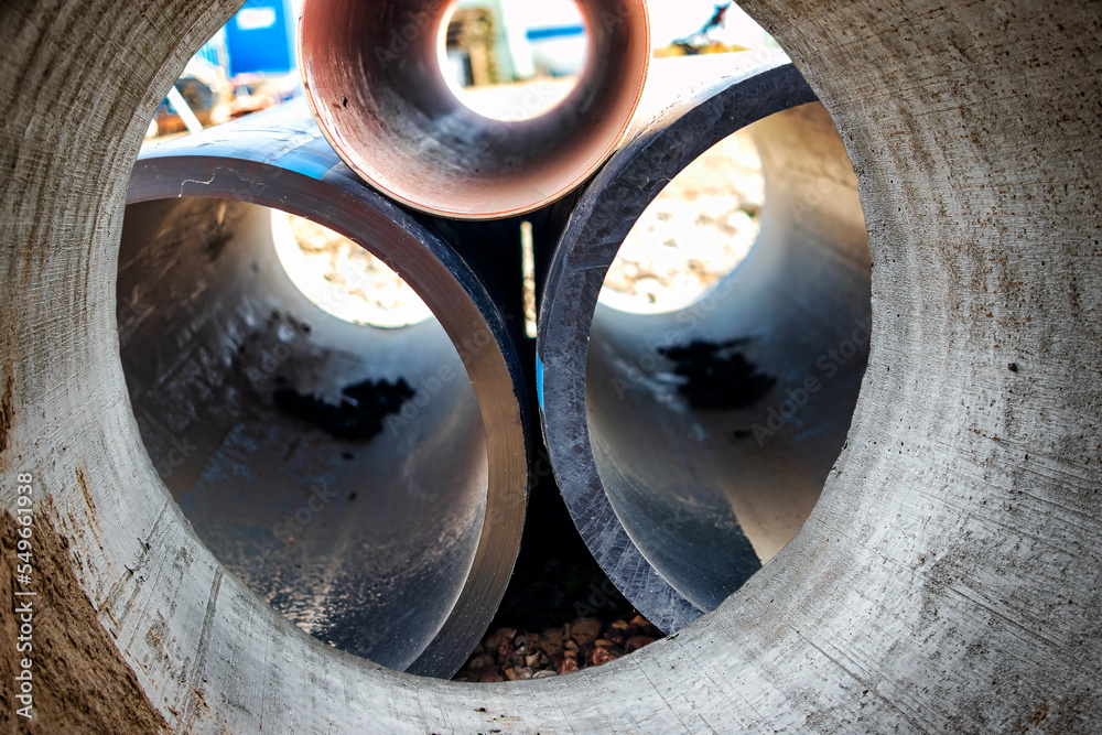 Water pipes for drinking water supply at a construction site. Underground pipeline works. Modern water supply systems for a residential city. Water supply at home. View from the big pipe. Water pipes for drinking water supply at a construction site. Underground pipeline works. Modern water supply systems for a residential city. Water supply at home. View from the big pipe.
