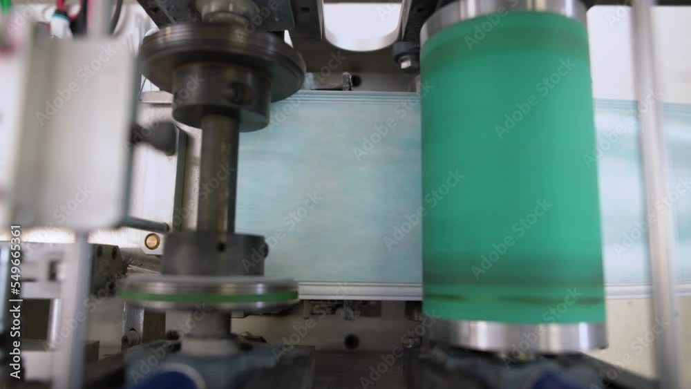 Closeup process of medical face masks being made in a factory. Automated machinery making respiratory medical masks in large quantities. Closeup process of medical face masks being made in a factory. Automated machinery making respiratory medical masks in large quantities.