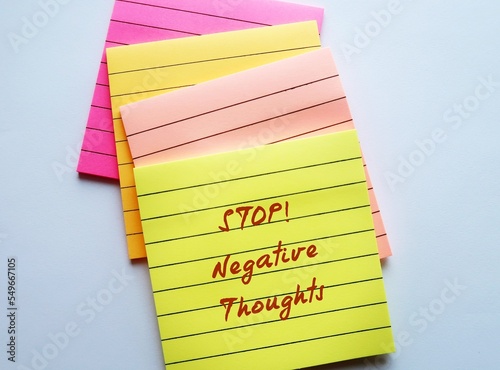 Paper Note on orange background with pen written STOP NEGATIVE THOUGHTS, means stop attracting negative life experiences, overcome and remove negative thinking and try not attract more painful events