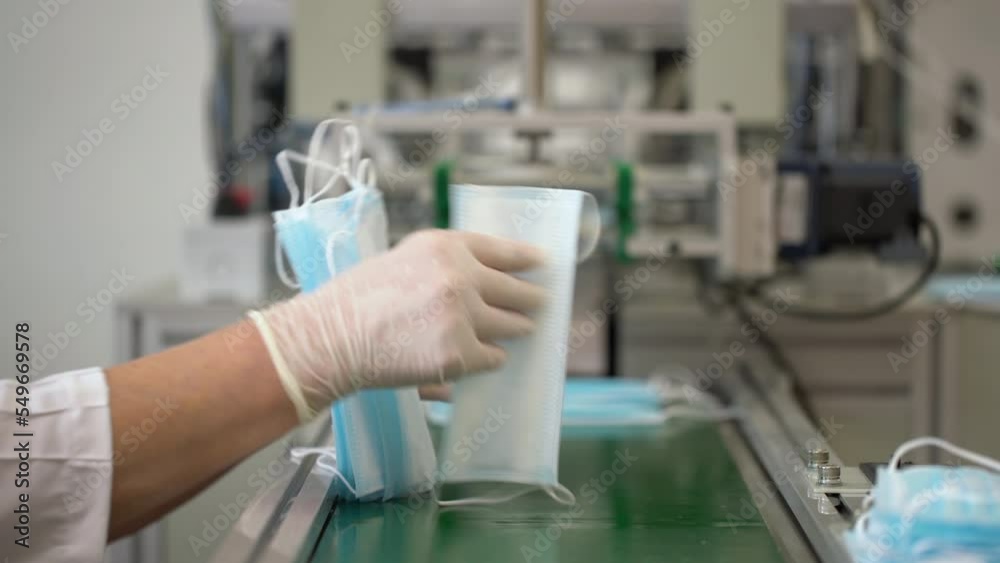 Close up of employees hands wearing gloves and packing medical face masks in a factory. Close up of employees hands wearing gloves and packing medical face masks in a factory.