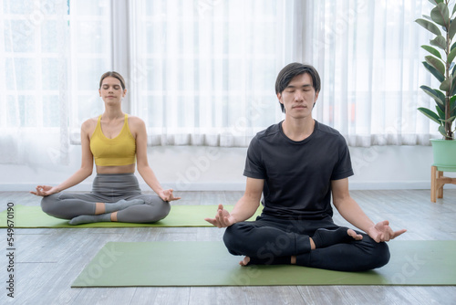 Couple exercising together, Man and woman in sportswear doing yoga together at home.