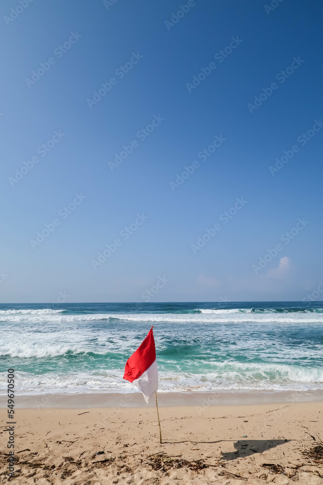 The flag of the Indonesian state that flutters against a blue sky and beach background. Usually flown on Independence Day on August 17th. The flag of the Indonesian state that flutters against a blue sky and beach background. Usually flown on Independence Day on August 17th.