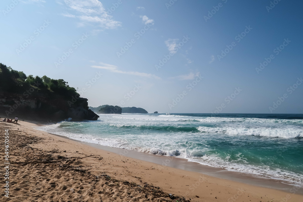 Beautiful beach with waves during the day with blue skies. Pantai Gunungkidul, Yogyakarta, Indonesia.