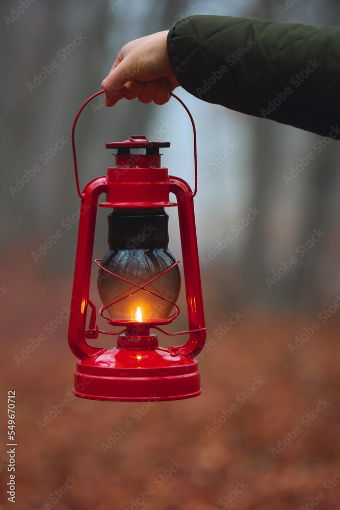A red kerosene lamp burns in a dark forest. The lamp illuminates the road in a dark forest.
