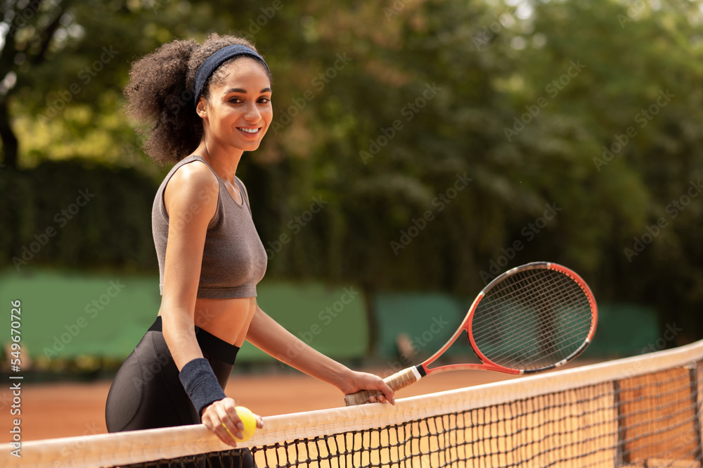 Cute dark-haired girl having a workout at the tennis court