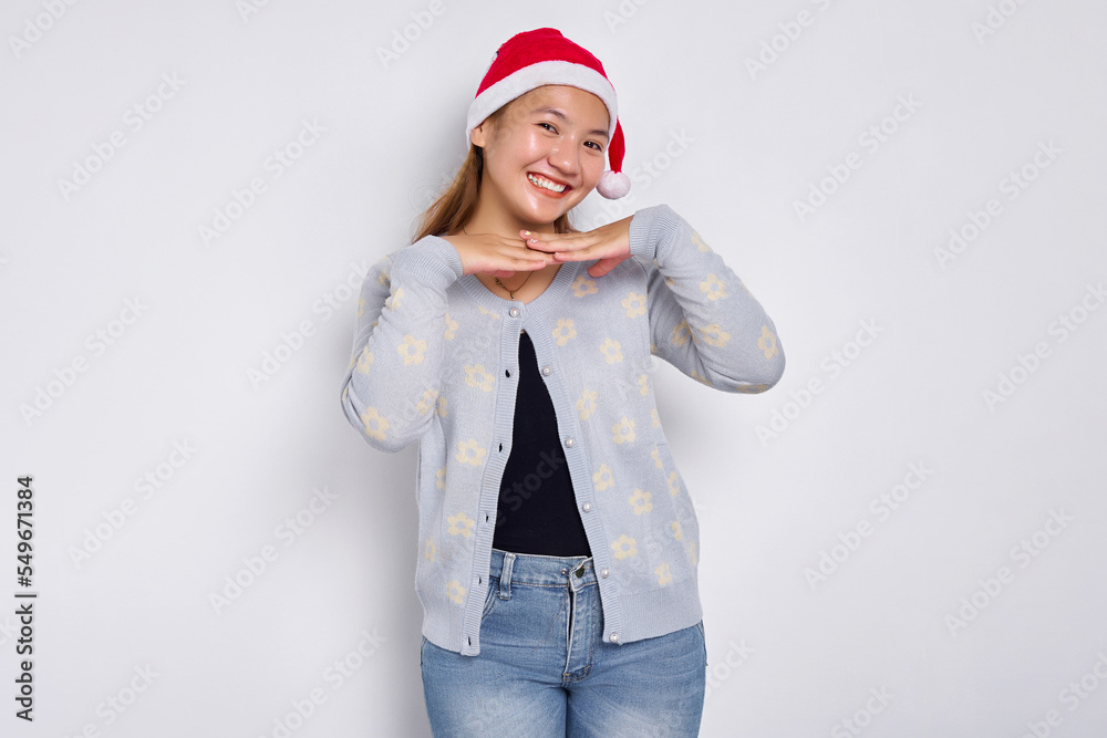 Attractive young Asian woman in Santa Claus hat smiling happy and looking confident over white background Attractive young Asian woman in Santa Claus hat smiling happy and looking confident over white background