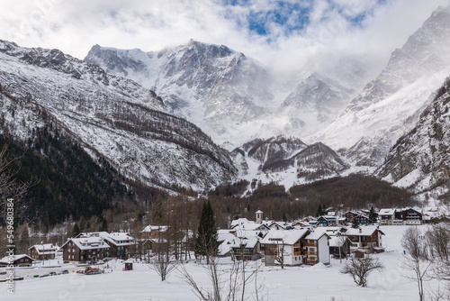 Traditional mountain village with snow. Macugnaga (Pecetto), Italy. Important ski resort in the European Alps with Monte Rosa partially shrouded in fog and clouds. Winter mountain landscape  © AleMasche72