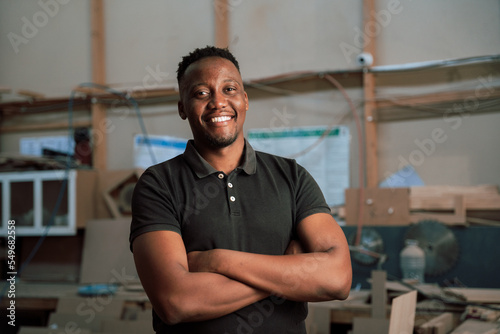 Young African man folding arms in factory
