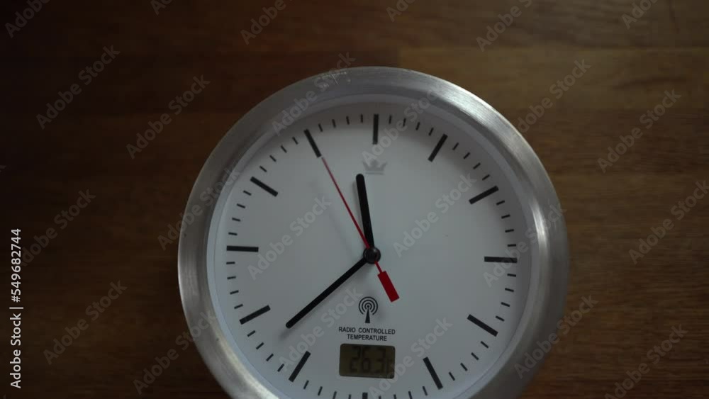 White clock ticking on wooden desk