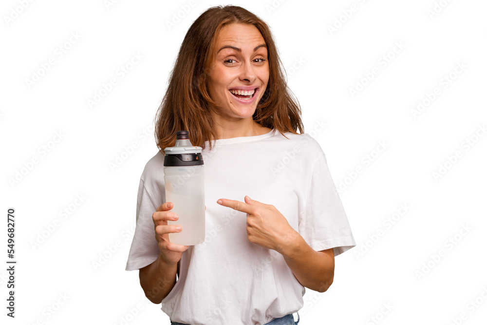 Young caucasian sport woman holding a bottle of water isolated smiling and pointing aside, showing something at blank space. Young caucasian sport woman holding a bottle of water isolated smiling and pointing aside, showing something at blank space.
