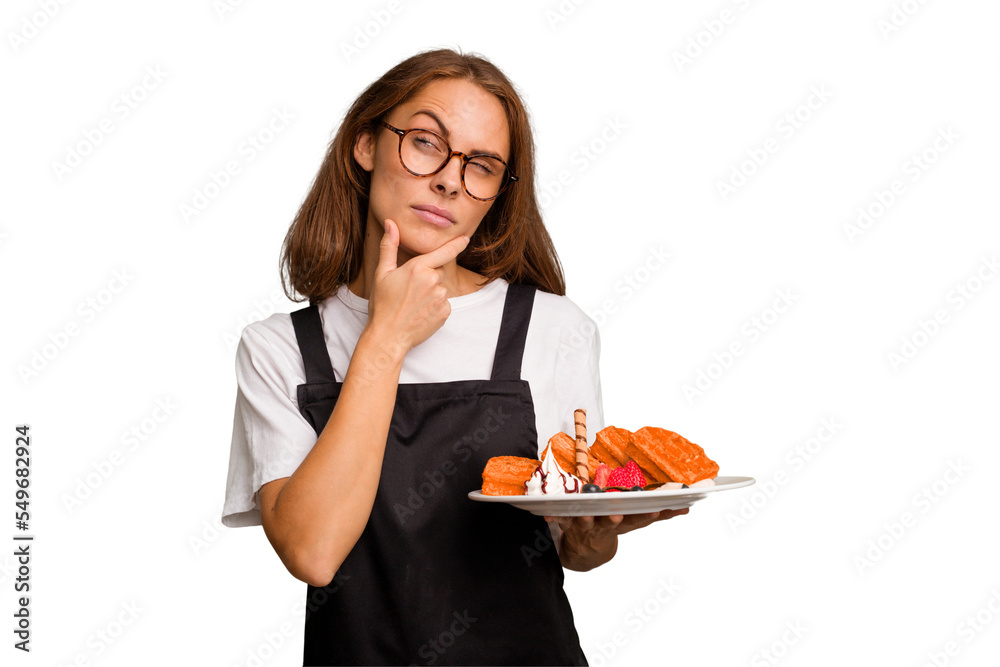 Young caucasian woman holding a waffles dish isolated looking sideways with doubtful and skeptical expression. Young caucasian woman holding a waffles dish isolated looking sideways with doubtful and skeptical expression.