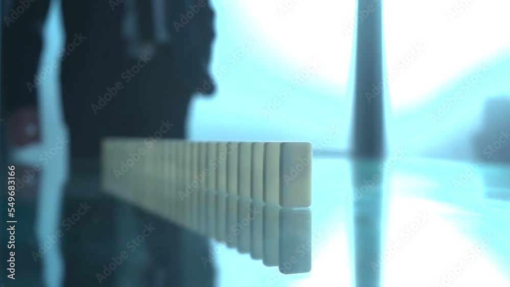 blurry image of a business man touching domino stones. blurry image of a business man touching domino stones.