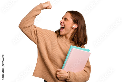 Young student woman holding a books isolated raising fist after a victory, winner concept.