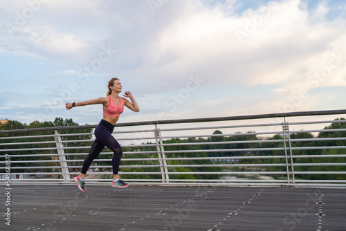 Fototapeta Naklejka Na Ścianę i Meble -  horizontal photo of strong woman running in the city, copy space, fitness concept