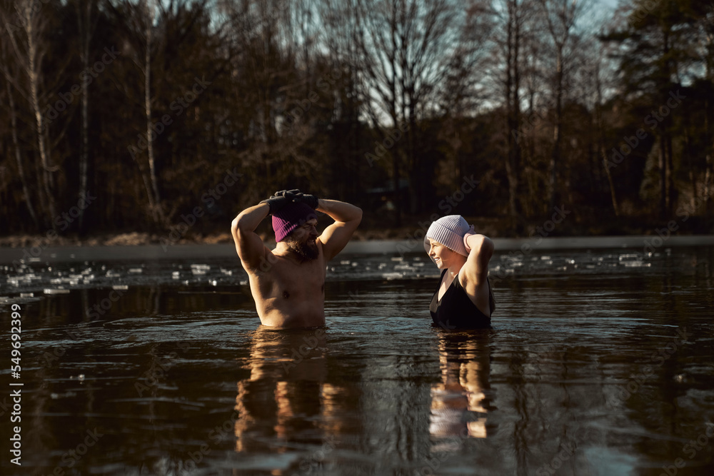 Fototapeta premium Caucasian couple standing and talking in frozen lake with hands raised