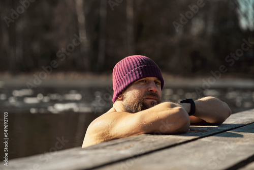 Caucasian adult man leaning in wooden pier in frozen lake