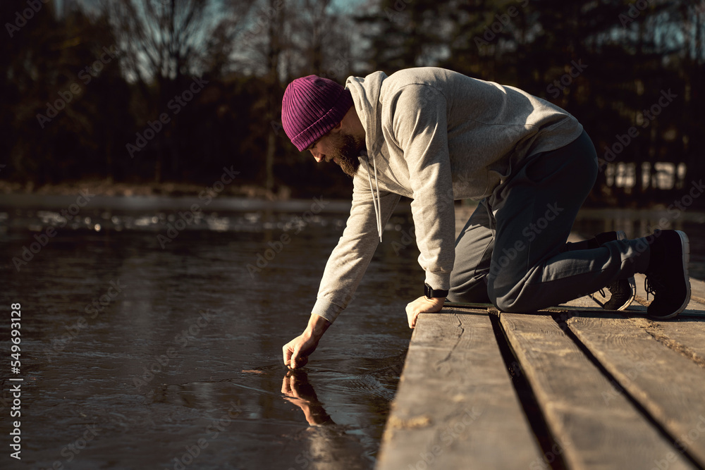 Caucasian adult man checking ice for swimming in frozen lake Caucasian adult man checking ice for swimming in frozen lake
