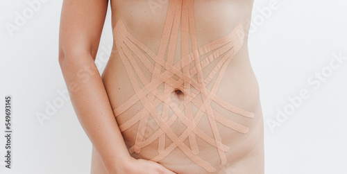 Women's body with kinesio tape on the abdomen. Kinesiology taping concept.