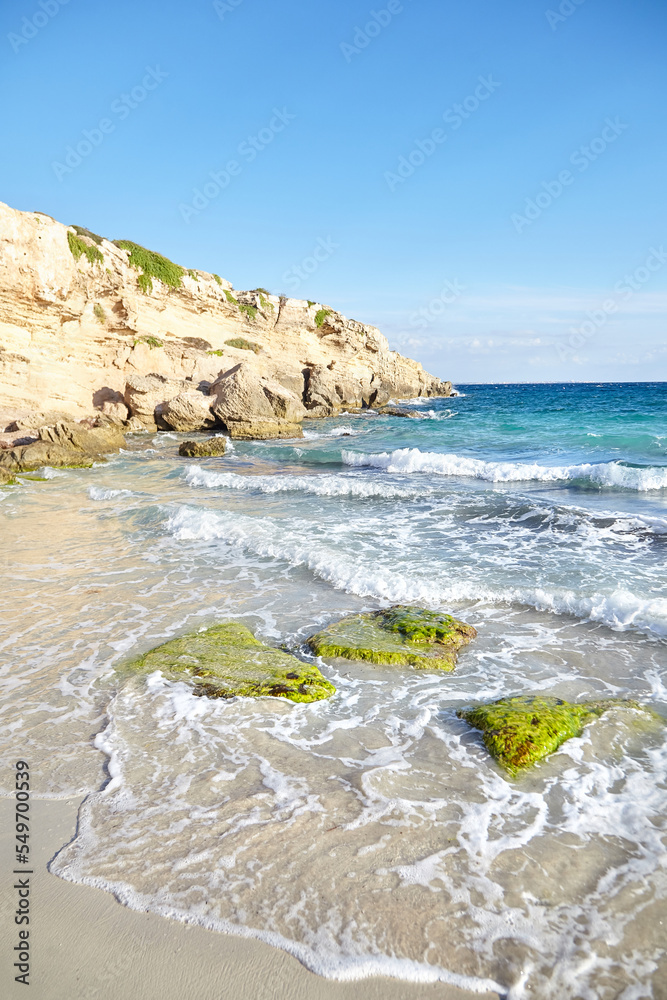 Sand beach near cliff, summer sea with blue sky. Sea water with white wave. Cala azzurra beach, Favignana island, Trapani, Sicily, Italy. A beautiful seascape