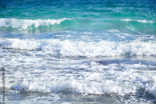 Summer sea water with white waves. Empty sand beach with azure water. Summer holiday background