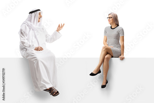Young woman sitting on a white panel and listening to a mature arab man talking