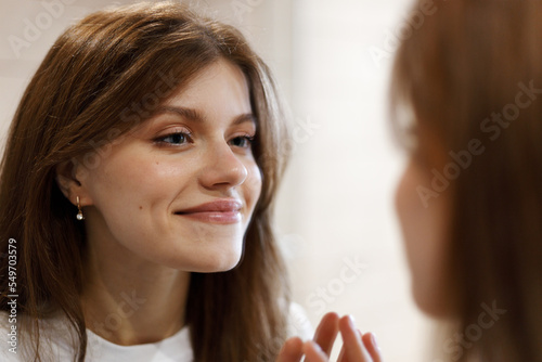 Smiling attractive woman in mirror reflection. Morning hygiene, positive mood.
