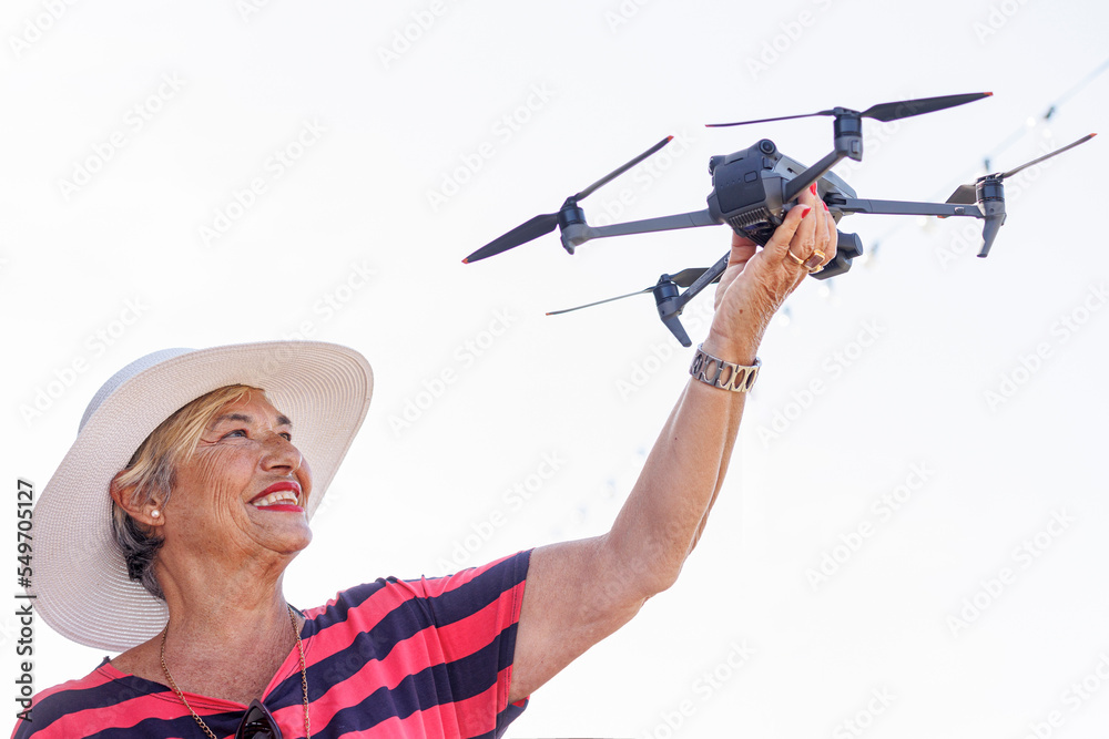 Anziana signora con un cappello tiene insano divertita un drone Anziana signora con un cappello tiene insano divertita un drone