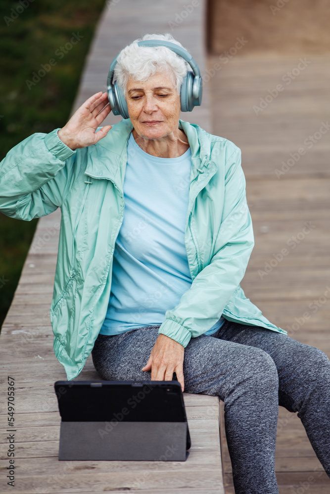 Fototapeta premium Grandmother in headphones with a tablet listens to music.