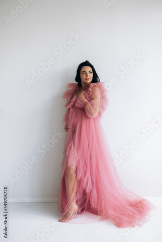 Beautiful pregnant woman in elegant dress posing to photographer in studio © andriyyavor